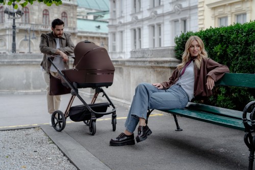 mama-siedząca-na-ławce-do-której-tata-pchający-wózek-z-gondolą